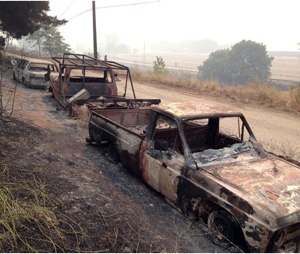 Burned cars sit along US Route 97, in Pateros, Wash., Friday. Authorities say the wildfire has already burned about 100 homes and prompted the evacuation of Pateros, home to about 650 people in Okanogan County. A hospital in nearby Brewster was also evacuated as a precaution. (AP Photo/The Seattle Times, Mike Siegel)