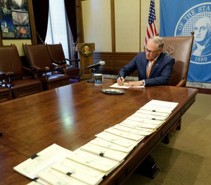 Washington Gov. Jay Inslee makes notes during a quiet moment during a bill signing ceremony, Tuesday, May 7, 2019, at the Capitol in Olympia, Wash.