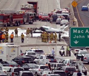 Emergency responders gather round the crash of a Cessna 310 aircraft on Interstate 405.