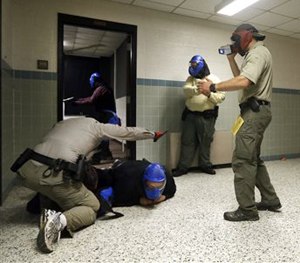 In this Aug. 13, 2013 photo, FBI instructor Mike Sotka, center, films local officers as they participate in an active shooter drill in a college classroom building in Salisbury, Md.