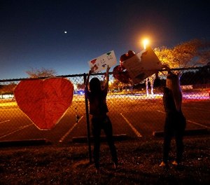 A student at Marjory Stoneman Douglas High School hangs signs on the fence of the school.