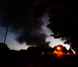 Light from a light pole shows a house near a plume of smoke from a Colonial Pipeline explosion. (AP Photo/Brynn Anderson)