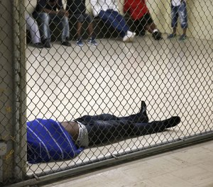 In this Thursday, June 26, 2014, photo a man lays on the floor of a holding cell at the Cook County Jail before his initial bond hearing in Chicago.
