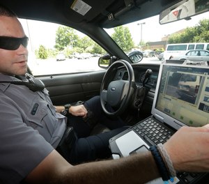 In this July 16, 2013, file photo, Officer Dennis Vafier, of the Alexandria Police Department, uses a laptop in his squad car to scan vehicle license plates during his patrols in Alexandria, Va.