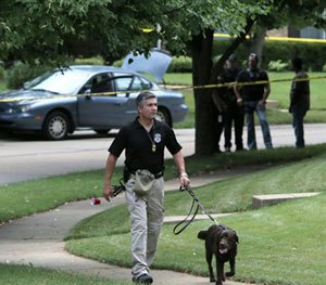 Police secure the scene and a suspect's vehicle in Ballwin, Mo., Friday, July 8, 2016, after a Ballwin police officer was shot during a confrontation with a man on a street. (AP Image)