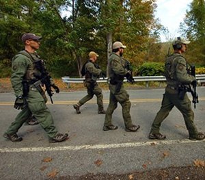Members of the FBI SWAT team walk to the woods Wednesday, Oct. 8, 2014, in Price Township near Canadensis, Pa., searching for killer Eric Frein.