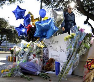 A woman leaves flowers at a make-shift memorial for slain San Antonio police officer Benjamin Marconi, 50, a 20-year veteran of the force, Monday, Nov. 21, 2016, in San Antonio.