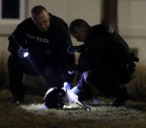 Police shine a light on a helmet as they investigate the scene where two police officers were shot outside the Ferguson Police Department Thursday, March 12, 2015, in Ferguson.