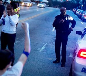 An officer stands watch while standing at an intersection during a protest against the shooting death of Anthony Hill by a police officer, in Decatur, Ga.