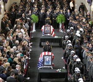 In this April 8, 2009 file photo family and officials pay their respects to the three Pittsburgh officers who were shot and killed while responding to a 911 call in Pittsburgh. (AP Photo/Gene J. Puskar, File)