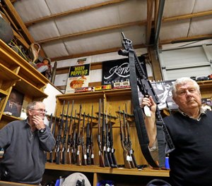 In this Oct. 20, 2017, file photo, sales clerk Tom Wallitner holds up a Mossberg 715T .22-caliber semi-automatic rifle during an auction at Johnny's Auction House, where the company handles gun sales for a half dozen police departments and the Lewis County Sheriff's Office, in Rochester, Wash. (AP Photo/Elaine Thompson, File)