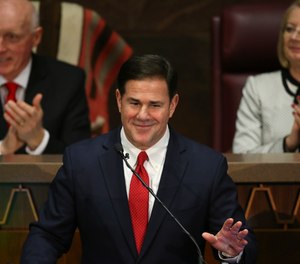 In this Jan. 13, 2020 file photo Arizona Republican Gov. Doug Ducey, foreground, gestures during his State of the State address.