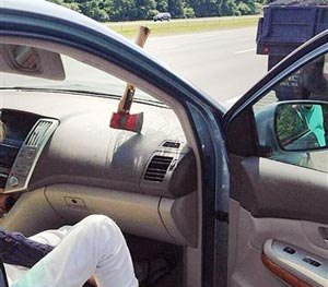 In a photo provided by Massachusetts State Police, an ax head rests on the dashboard with the handle stuck in the windshield of a motorist's car after falling off a landscaper's truck on Route 95 in Topsfield, Mass., Wednesday July 30, 2014.
