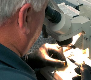 Fort Bend County Sheriff's Office crime scene investigator Dominic Sodolak examines a bullet casing in his Richmond, Texas office, from ammunition that was test fired from a handgun confiscated during a drug arrest. (Photo/AP)