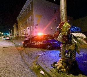 A previously created memorial, right, stands as Baltimore police work at a scene where multiple people were shot in Baltimore, Saturday night, Sept. 24, 2016.