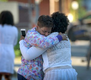 Two women embrace in an alley behind the Man Alive drug treatment center in Baltimore shortly after a shooting. (Jerry Jackson/The Baltimore Sun via AP)