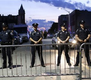 Members of the Baltimore Police Department stand behind barriers outside of the Western District police station during a march for Freddie Gray. (AP Image)