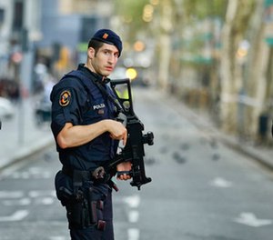 Armed police officers patrol a deserted street in Las Ramblas, in Barcelona, Spain, Friday, Aug. 18, 2017.
