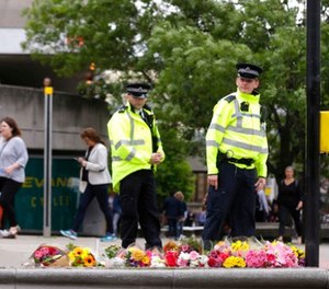 Police officers walk by floral tributes in the London Bridge area of London, Monday, June 5, 2017. (AP Photo/Alastair Grant)