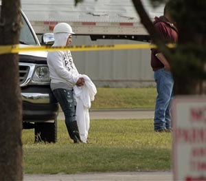 Employees wait in the parking lot as police investigate a shooting at Vaughan Foods on Thursday, Sept. 25, 2014 in Moore, Okla.
