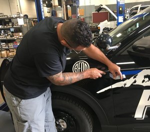 A man removes a thin blue line decal from a Bend Police Department patrol car.