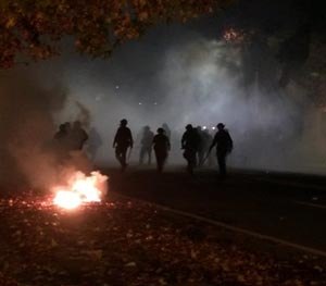 In this photo provided by Tay Nitta, police in riot gear patrol a street in Berkeley, Calif. amid smoke and tear gas after a protest over police killings turned violent, early Sunday, Dec. 7, 2014. (AP Image)
