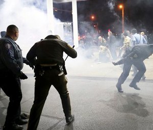 Police try to control a crowd Wednesday, Dec. 24, 2014, on the lot of a gas station following a shooting Tuesday in Berkeley, Mo.