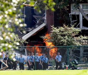 Emergency personnel move away as a gas fire continues to burn following an explosion at Minnehaha Academy.