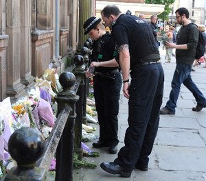 Police look at floral tributes left at St Ann's square, Manchester, England Tuesday May 23, 2017. (AP Photo/Rui Vieira)