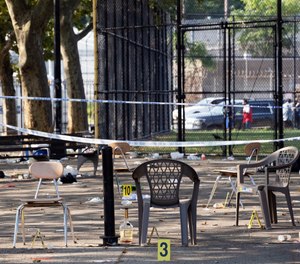 Yellow evidence markers are placed next to chairs at a playground in the Brownsville neighborhood in the Brooklyn borough of New York, Sunday, July 28, 2019. (AP Photo/Mark Lennihan)