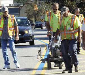 In this Sept. 12, 2016 photo, Wayne, N.J., Department of Public Works employees paint blue line in middle of solid yellow lines on a roadway.