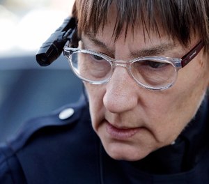 In this Thursday, March 12, 2015, file photo, Seattle police officer Debra Pelich wears a video camera on her eyeglasses, part of a pilot program testing the cameras, as she talks with a local citizen before a small community gathering in Seattle.