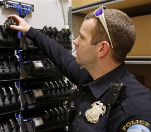 In this Feb. 2, 2015 photo, Duluth, Minn., police officer Dan Merseth demonstrates the docking procedure for police body cameras at police headquarters.