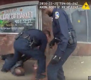 In this image taken from video from a body camera worn by a Baltimore police officer on Monday, Nov. 25, 2016, three officers attend to a man that was shot in Baltimore. The police officers shot the man who was threatening people with knives at a bus stop.