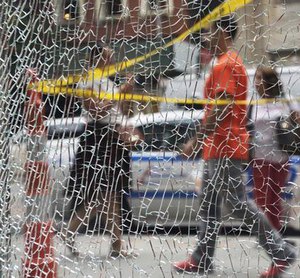 New Yorkers pass a shattered storefront window on W. 23rd St. in Manhattan, Tuesday, Sept. 20, 2016, in New York. (AP Photo/Mark Lennihan)