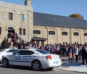 In this Monday, Oct. 6, 2014 photo, Massachusetts College of Liberal Arts students, faculty and staff are evacuated into the armory in North Adams, Mass., following a bomb threat on campus. The school was evacuated for three hours until the campus was deemed safe. Nearly a dozen public schools and colleges in Massachusetts, New Hampshire and Connecticut have received threats forcing evacuations and cancellations in the past week. (AP Photo/The Berkshire Eagle, Gillian Jones)
