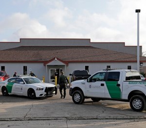 A U.S. Border Patrol Agent walks between vehicles outside the Central Processing Center in McAllen, Texas (AP Photo/David J. Phillip, File)