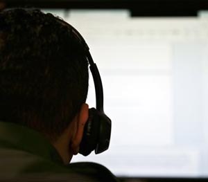 In this June 5, 2014 photo, a Border Patrol agent uses a headset and computer to conduct a long distance interview by video with a person arrested crossing the border in Texas, from a facility in San Diego. (AP Image)