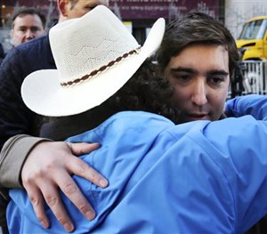 Boston Marathon survivor Jeff Bauman, right, is embraced by Carlos Arredondo, who helped save his life, near the finish line of the Boston Marathon in Boston, Wednesday, April 15, 2015.