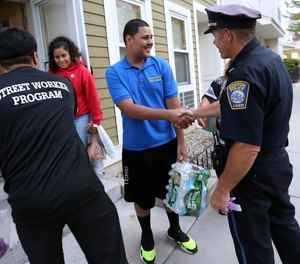 In this Sept. 20, 2018 photo, Francisco Melger, left, of the Boston Center for Youths and Family, and Police Officer Dan Long greet East Boston residents during a Walk for Peace and Unity. Nearly three years after the nation's largest single takedown of MS-13 gang members, residents in the strongly Central American communities around Boston say the streets are noticeably quieter.