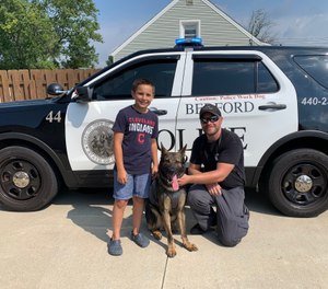 Brady Snakovsky, 10, stands with a Bedford Police officer after donating a vest to K-9 Luca on August 25, 2020 in Bedford, Ohio. (Photo/Bedford Police Department)