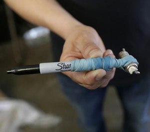 In this May 12, 2016 photo, Julio Lara, manager at Auto Glass Now, holds up a spark plug attached to a Sharpie pen used to break a car window while interviewed in San Francisco. (AP Image)