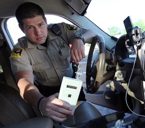 In this Sept. 21, 2015 photo, Minnehaha County Deputy Sheriff Elliott Crayne installs a car breathlyzer for a participant in the state's 24/7 Sobriety Program outside the county jail in Sioux Falls, S.D.