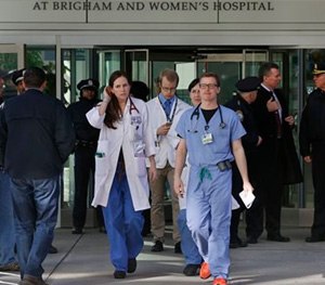 Medical personnel walk past law enforcement officials, right, as they depart the Shapiro building at Brigham and Women's Hospital, in Boston.