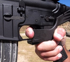 Shooting instructor Frankie McRae illustrates the grip on an AR-15 rifle fitted with a