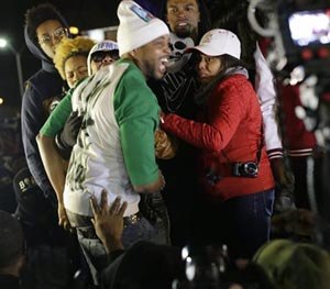 In this Nov. 24, 2014 file photo Louis Head, center front, Michael Brown's stepfather, and Brown's mother Lesley McSpadden, wearing sunglasses, react as they listen to the announcement that a grand jury decided not to indict Ferguson police officer Darren Wilson who fatally shot Brown. (AP Image)