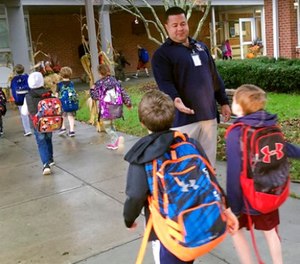 In this Nov. 6, 2017 photo, campus monitor Hector Garcia greets students as they got off the bus at the start of the school day at West Elementary School in New Canaan, Conn. (AP Photo/Michael Melia) 
