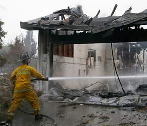 A Santa Rosa firefighter hoses down a hotspot in the Coffey Park area of Santa Rosa, Calif.