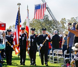 A U.S. flag hangs from the ladder of a fire truck as a color guard comprised of Santa Rosa firefighters presents the colors to start a Day of Remembrance memorial for victims of California wildfires.
