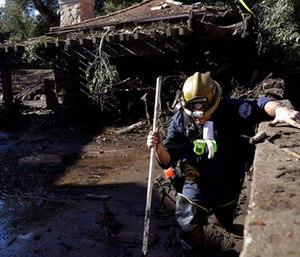 Alex Broumand of the Montecito Fire Department walks in mud in front of homes damaged from storms in Montecito, Calif.